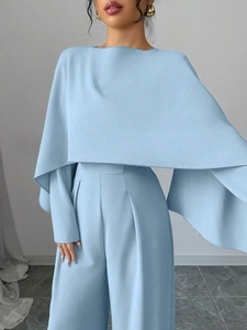 Detail of elegant light blue jumpsuit featuring cape sleeve top and wide leg high waist pants
