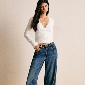 Slim fit white long sleeve knit top with V-neck lace trim and dark blue wide-leg jeans