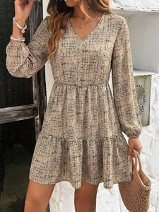 Detail of elegant long sleeve V-neck dress with abstract grid print and tiered skirt