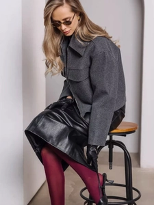 Dettaglio della giacca di lana grigia con colletto a rever e grandi tasche su modella