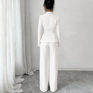 Vue de dos d'un tailleur blanc deux pièces avec blazer ceinturé et pantalon large