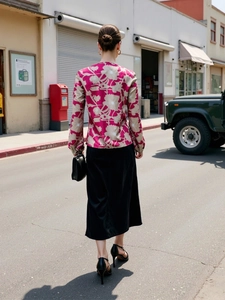Street style view of woman in pink floral long sleeve blouse and black satin midi skirt
