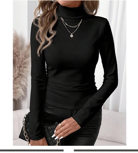 Detail of slim fit black high neck sweater styled with gold jewelry and a quilted bag