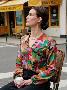 Detail of colorful tropical floral print on satin V-neck long sleeve blouse for women