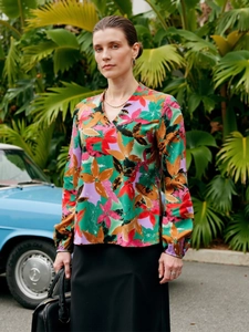 Detailed close-up of V-neck floral blouse with elastic cuffs and vibrant tropical patterns