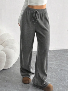 Dettaglio dei pantaloni larghi a righe grigio scuro con coulisse a vita alta e costine