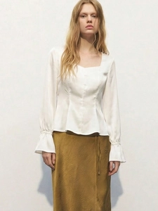 Dettaglio di elegante camicetta in raso bianco con scollo quadrato e maniche a lanterna