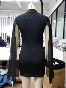 Détail d'une robe moulante noire avec manches fendues effet cape et paillettes argentées