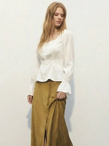Dettaglio dell'elegante camicia in raso bianco con scollo quadrato e maniche a sbuffo