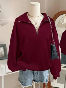 Detail of half-zip stand collar on a burgundy oversized sweatshirt with fleece lining