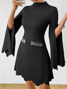 Detail of elegant black slim-fit dress featuring flared sleeves and rhinestone waist accents