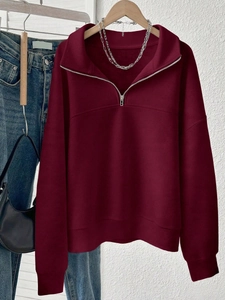 Detail of burgundy half-zip sweatshirt with ribbed cuffs and high-collar metallic zipper