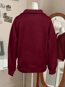 Detail of burgundy stand collar sweatshirt showing ribbed cuffs and soft cotton texture