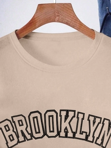 Detail of Brooklyn print and neckline stitching on beige cotton short sleeve t-shirt