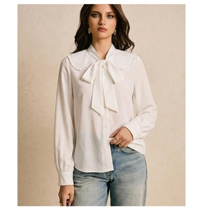 Detail of white long sleeve blouse with ruffled Peter Pan collar and large bow tie