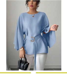 Detail view of light blue blouse featuring elegant flare sleeves and a gold buckle belt