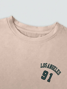Detail des Los Angeles-Drucks auf beige Baumwoll-T-Shirt mit verstärktem Rundhals-Ausschnitt