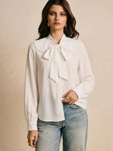 Detail view of white long-sleeve blouse with ruffle Peter Pan collar and large bow tie