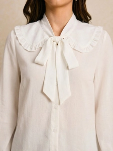 Detailed view of the ruffle Peter Pan collar and bow tie on white cotton shirt