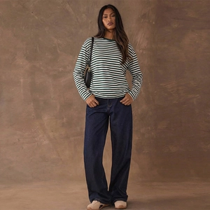 T-shirt femme à rayures et jean en denim large sur un fond studio de couleur marron