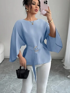 Detail of elegant sky blue blouse featuring flared mid-sleeves and waist belt with gold buckle