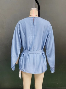 Detail view of light blue satin blouse featuring a stylish self-tie waist belt on the back