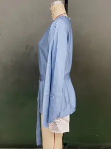 Detail of light blue satin blouse showing side waist tie and smooth texture finish