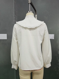 Detail view of white long-sleeved shirt with ruffle collar and wide sailor neckline