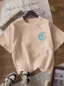 Detail of apricot crewneck T-shirt with sun and moon graphic on wooden floor