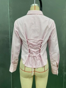 Detail of pink and white striped shirt featuring a back lace-up cutout and slim waist