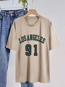 Détail d'un t-shirt beige avec imprimé Los Angeles 91 sur cintre avec un jean bleu