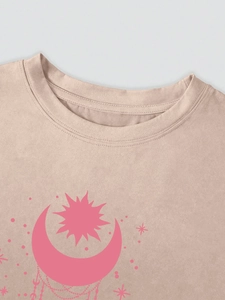 Détail du col rond et de l'imprimé soleil lune sur un t-shirt couleur abricot