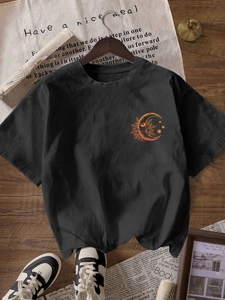 Detailed flat lay of black crewneck T-shirt with orange moon and sun celestial print