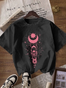 T-shirt noir pour femme avec imprimé céleste rose soleil et lune sur un cintre en bois