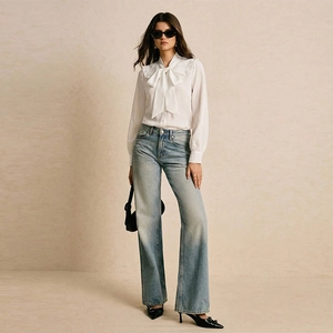 Women's white long sleeve blouse with bow collar paired with high waisted blue jeans