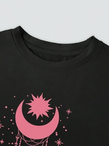 Gros plan du t-shirt noir avec imprimé céleste rose soleil, lune et étoiles sur le devant