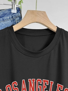 Détail d'un t-shirt noir en coton avec imprimé Los Angeles sur un cintre en bois