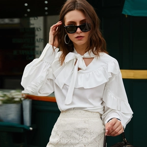 Detail of white long sleeve blouse with ruffled edges and elegant neck tie bow