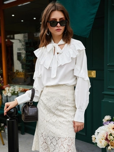 Chic white chiffon blouse with ruffle details and bow neck paired with lace skirt