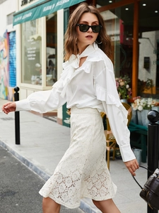Fashionable white ruffle blouse with tie-neck and lace skirt for a chic urban street look