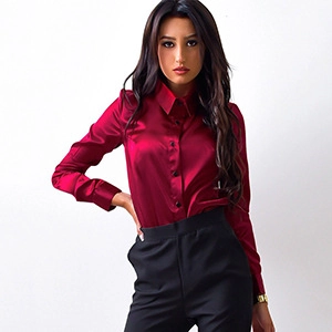 Detail of burgundy satin long sleeve shirt with polished buttons and smooth silk texture