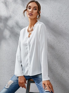 Detail of white ruffle long sleeve blouse featuring V-neck and delicate button closure