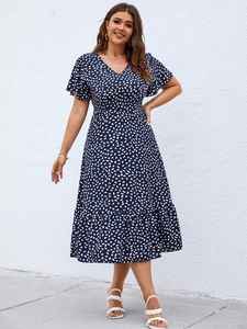 Detail of navy blue V-neck dress with white teardrop polka dots and ruffle sleeves