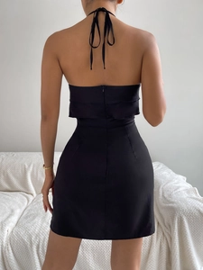 Detail of backless black halter dress featuring ruffled layers and lace-up back design