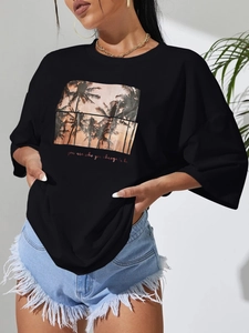 Women's black loose round neck T-shirt featuring a palm tree sunset print and denim shorts