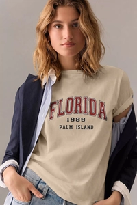 Close-up of beige cotton T-shirt featuring Florida 1989 graphic with layered navy blazer