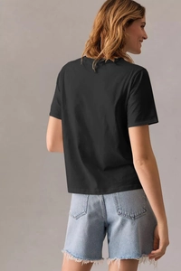 Vue arrière d'un t-shirt noir décontracté pour femme avec un short en jean effiloché