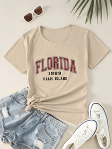 Flat lay of Florida 1989 printed khaki t-shirt with summer vacation styling and props