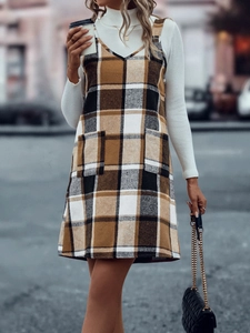Detailansicht des karierten Trägerkleids mit zwei Taschen und weißem Rollkragenpullover