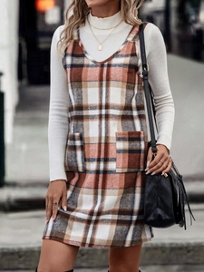 Outdoor-Streetstyle einer Frau in einem orangefarbenen karierten Trägerkleid mit Taschen